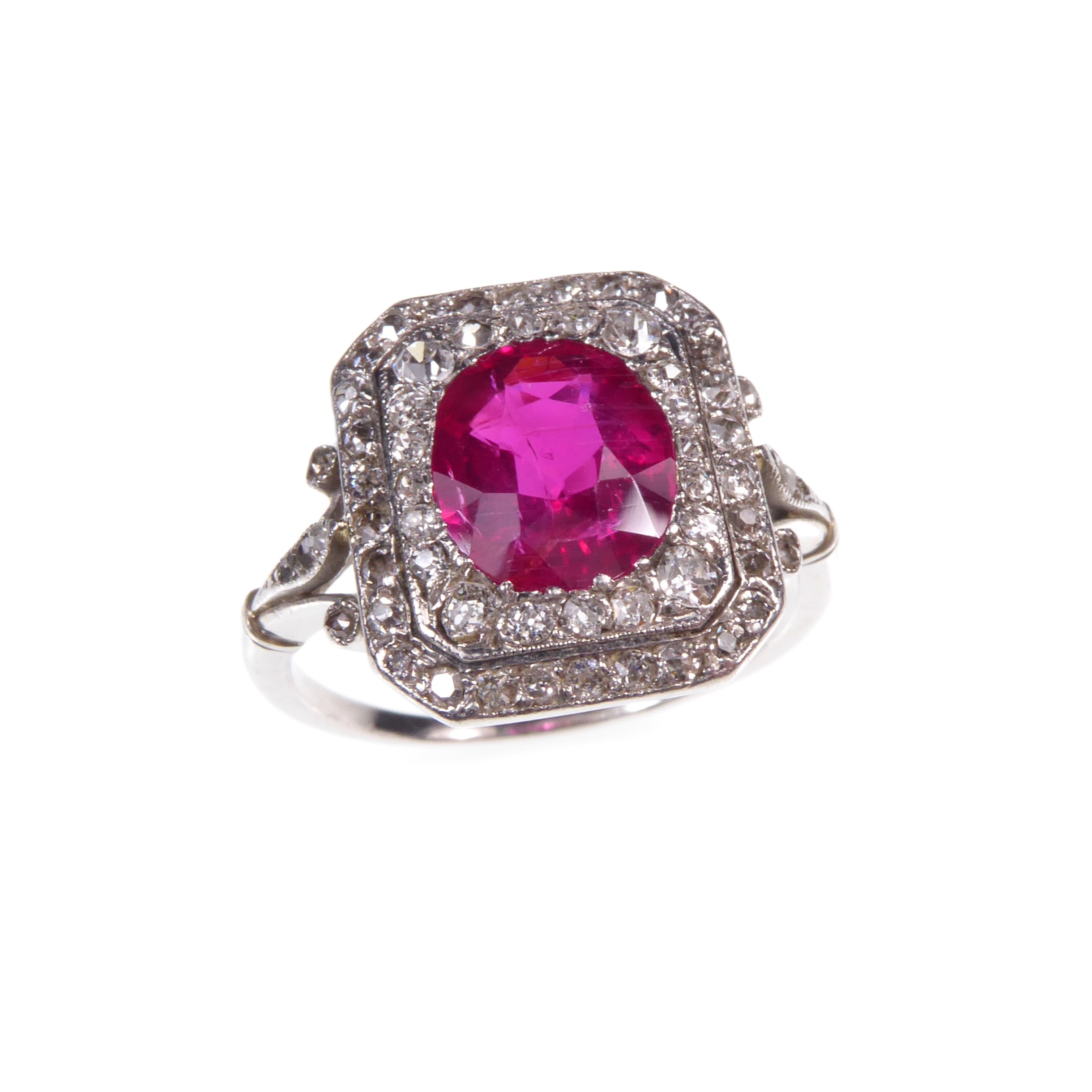 Early 20th century ruby and diamond cluster ring, c.1910, the oval facetted Burma ruby of approximately 2.60ct, to a cut-corner rectangular diamond set double border,